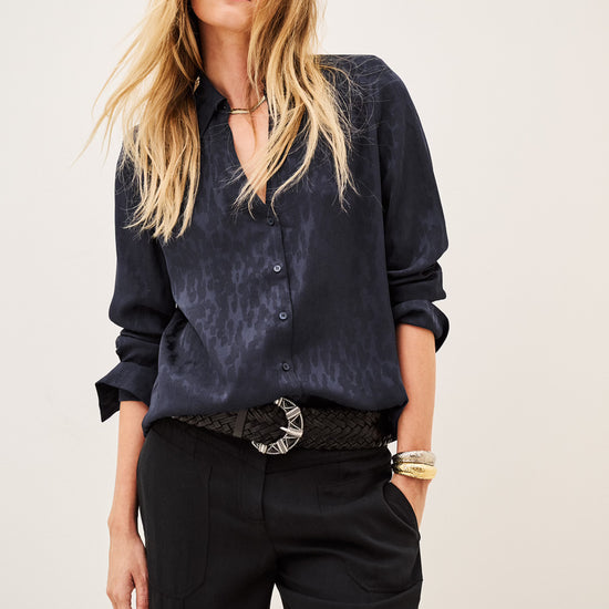 Woman wearing blue shirt and black trousers on white background close up