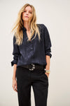 Woman wearing blue shirt and black trousers on white background close up