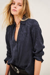 Woman wearing blue shirt and black trousers on white background side view