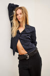 Woman wearing blue shirt and black trousers on white background posing