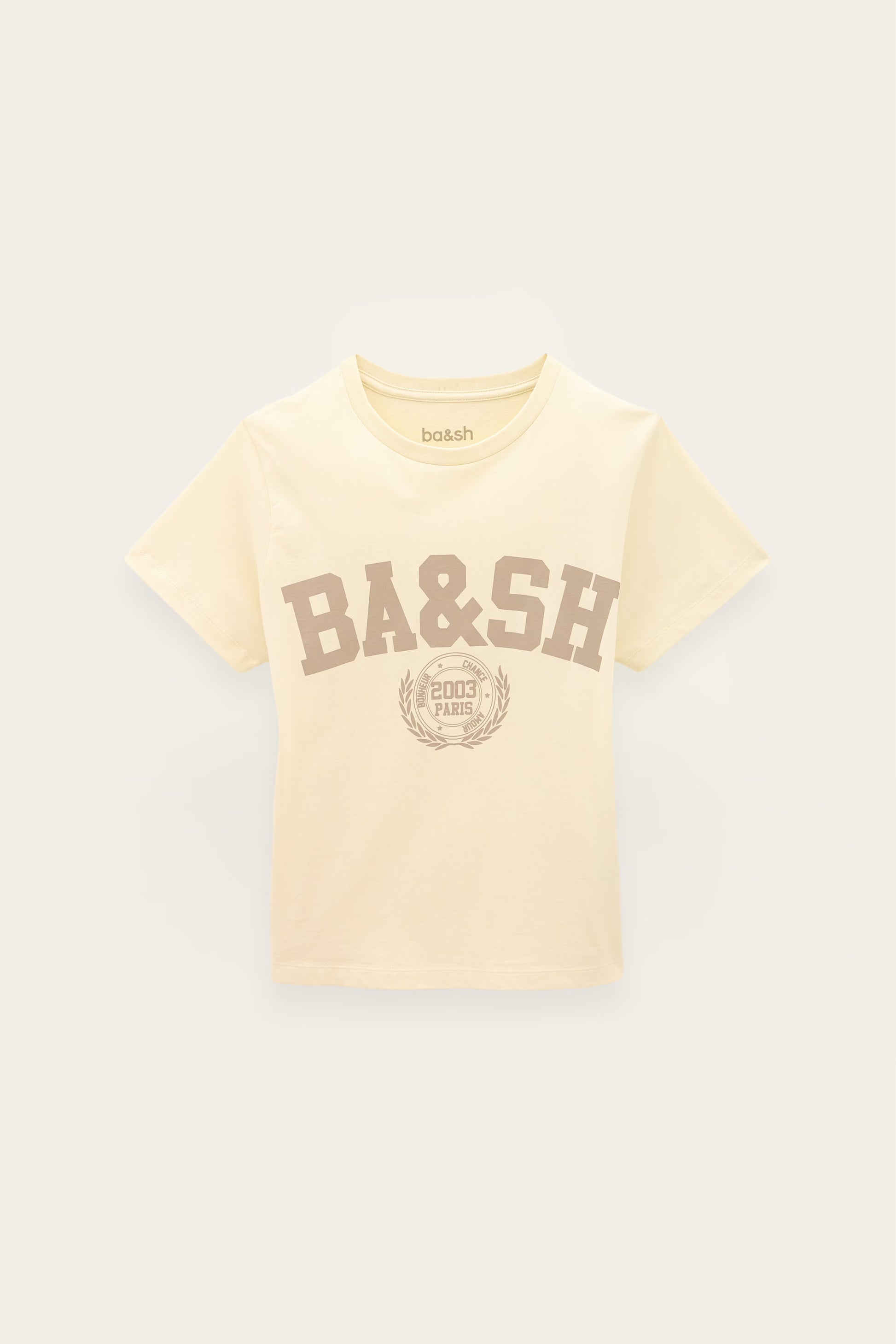 A cream-colored short-sleeve t-shirt with a brown 'BA&SH' collegiate-style graphic on the front, displayed against a light off-white background.