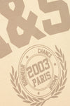 Beige textured surface with embossed or printed taupe-brown typography, including large stylized numbers at the top and a circular emblem reading '2003 PARIS' with surrounding text and laurel branches.