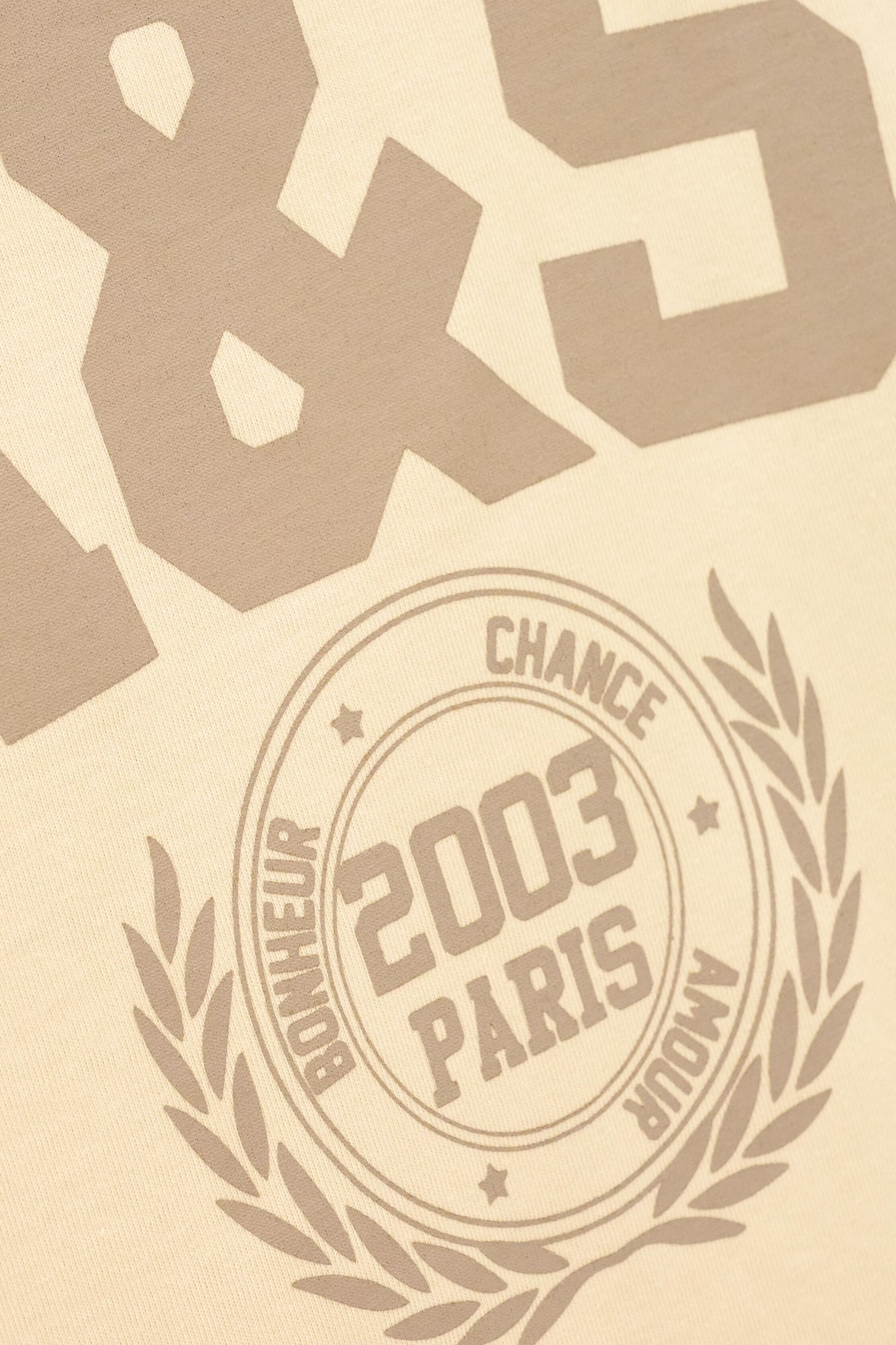 Beige textured surface with embossed or printed taupe-brown typography, including large stylized numbers at the top and a circular emblem reading '2003 PARIS' with surrounding text and laurel branches.