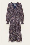 A long-sleeve midi dress with a dense multicolor floral print on a dark navy base, featuring a V-neckline and gathered waist, shown flat against a light cream background.