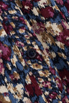 Close-up of a textured fabric with an abstract ikat pattern in navy blue, burgundy, beige, and brown, featuring a dark button.