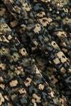 Close-up of a textured fabric with a dense abstract floral or pixelated pattern in black, olive green, beige, and muted blue-gray.