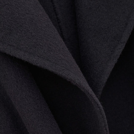 Close-up of a dark charcoal gray or black textured fabric with soft draped folds and a fine woven surface.