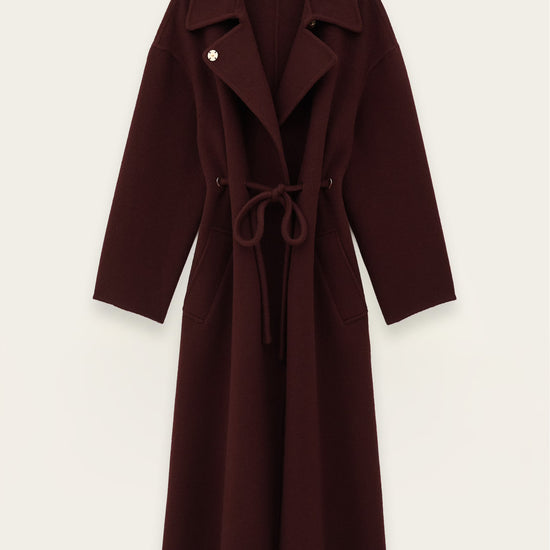 A dark burgundy wool-blend coat with a tie belt and notched lapels, shown flat against a light off-white background.