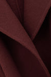 A close-up of draped burgundy wool fabric with soft folds and a fine napped texture.