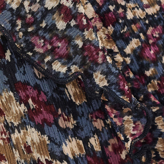 Close-up of a textured jacquard fabric with an abstract floral pattern in navy blue, burgundy, beige, and muted gold.