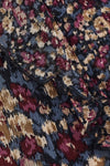 Close-up of a textured jacquard fabric with an abstract floral pattern in navy blue, burgundy, beige, and muted gold.