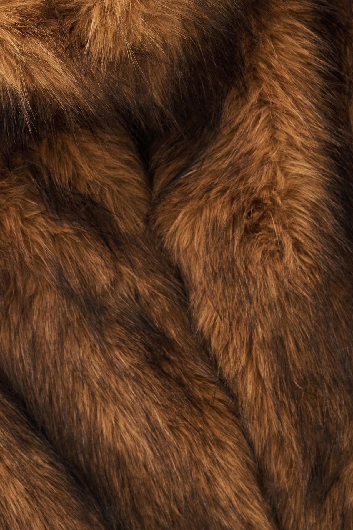 A close-up of rich brown faux fur fabric with soft, shaggy texture and darker shadowed areas.