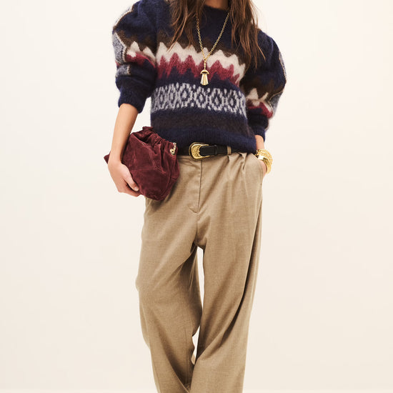 Woman wearing beige tailored trousers and a sweatshirt on a white background
