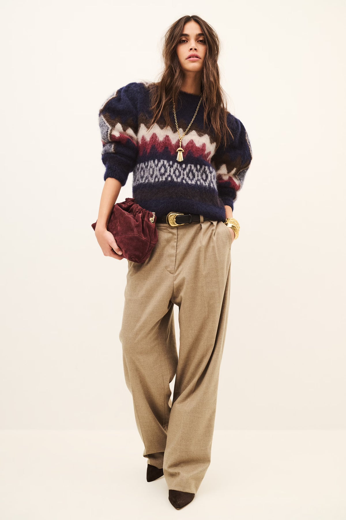 Woman wearing beige tailored trousers and a sweatshirt on a white background