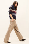 Woman wearing beige tailored trousers and a sweatshirt on a white background side view