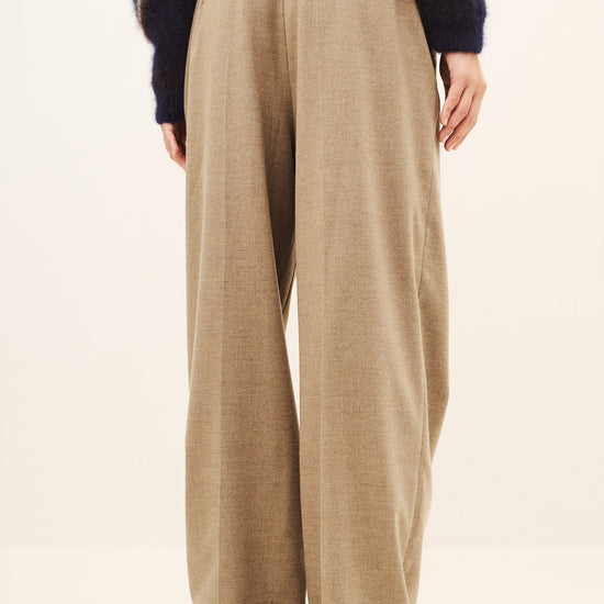 Woman wearing a beige pair of trousers and a jumper rear view