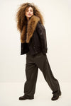 Woman wearing brown trousers and coat on a white background