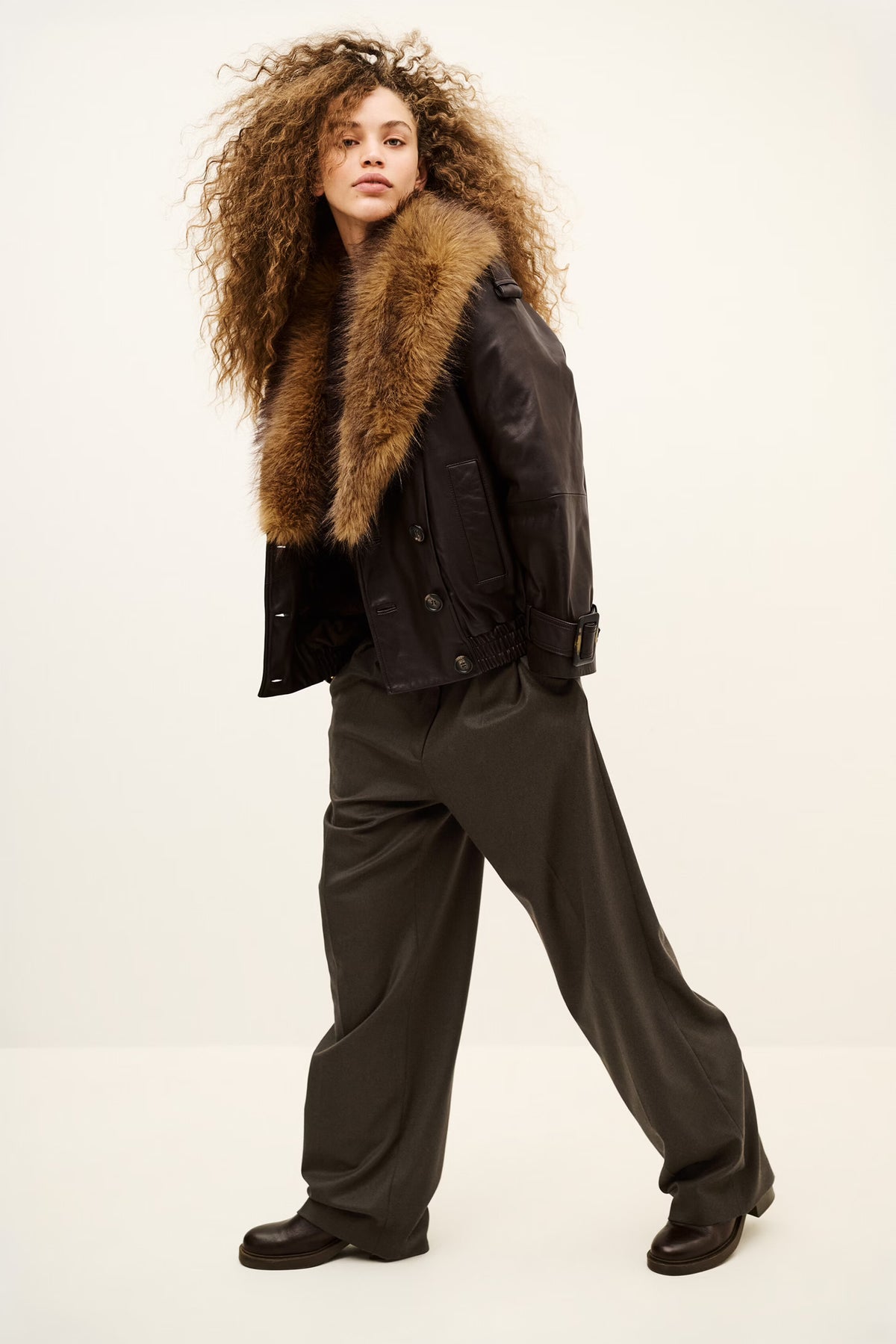 Woman wearing brown trousers and coat on a white background