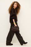 Woman wearing brown trousers and jumper on a white background side view