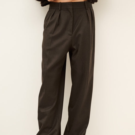 Woman wearing brown trousers and jumper on a white background