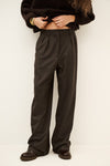 Woman wearing brown trousers and jumper on a white background