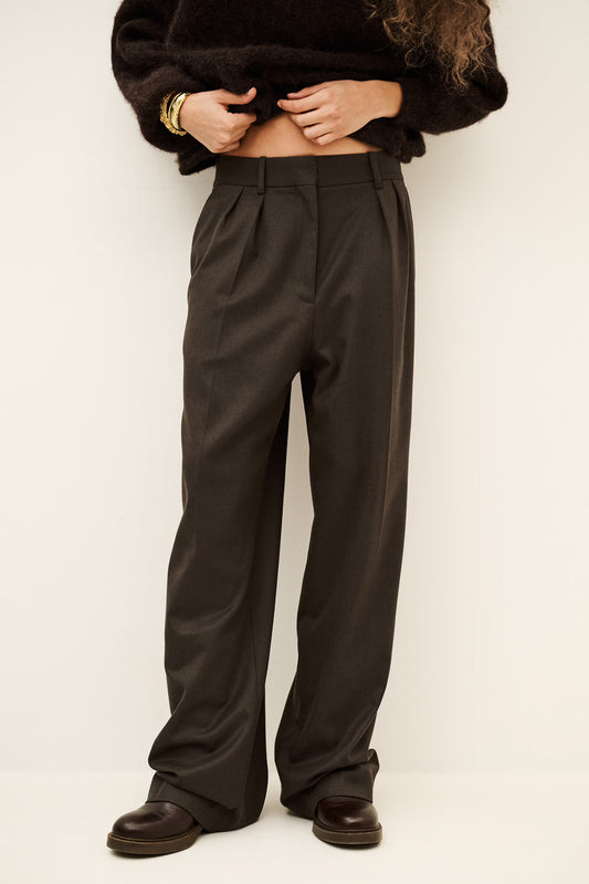 Woman wearing brown trousers and jumper on a white background