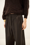 Woman wearing brown trousers and jumper on a white background close up of front