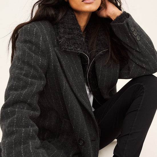model wearing a grey pinstripe wool coat  and white t shirt side view