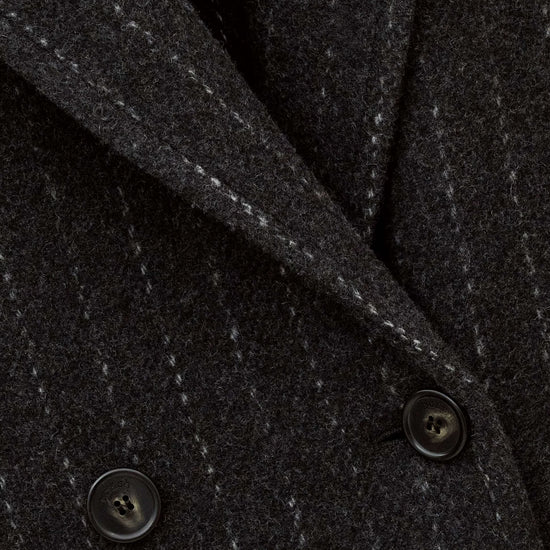 Close-up of a dark charcoal gray pinstripe wool-blend jacket fabric, showing the fine vertical stripe pattern and dark buttons.