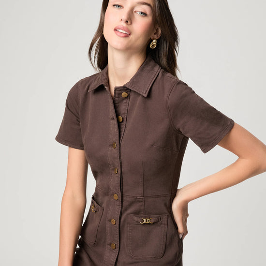 Woman wearing a brown short-sleeve shirt with buttons on a light gray background