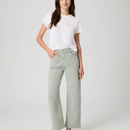 Woman wearing a white t-shirt and light green by Paige pants on a white background