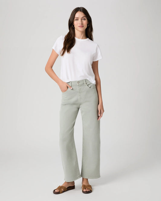 Woman wearing a white t-shirt and light green by Paige pants on a white background