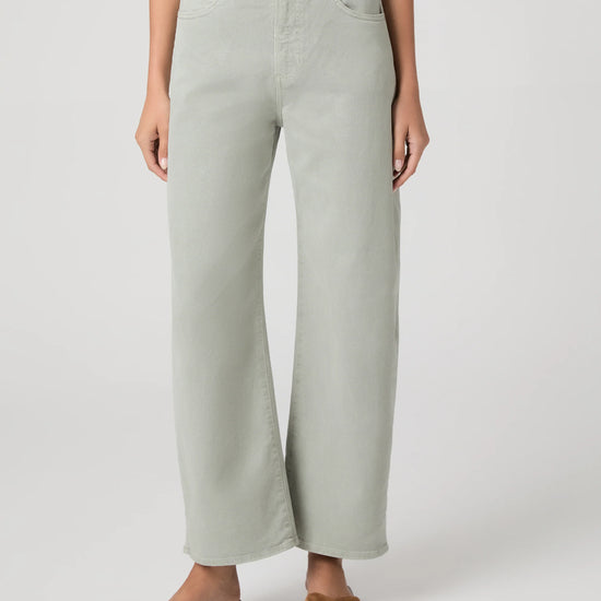 Person wearing light green wide-leg paige jeans on a white background