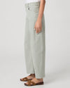 Person wearing light green wide-leg paige jeans on a white background side view