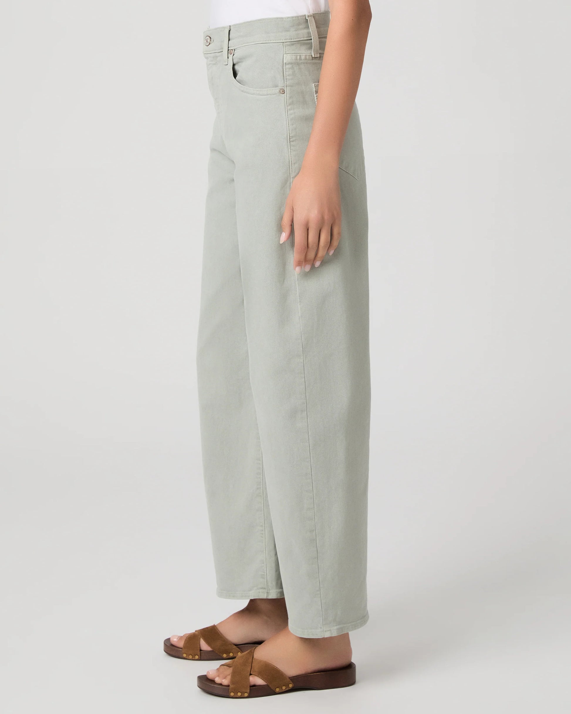 Person wearing light green wide-leg paige jeans on a white background side view