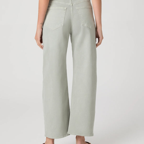 Person wearing light green wide-leg paige jeans on a white background rear view