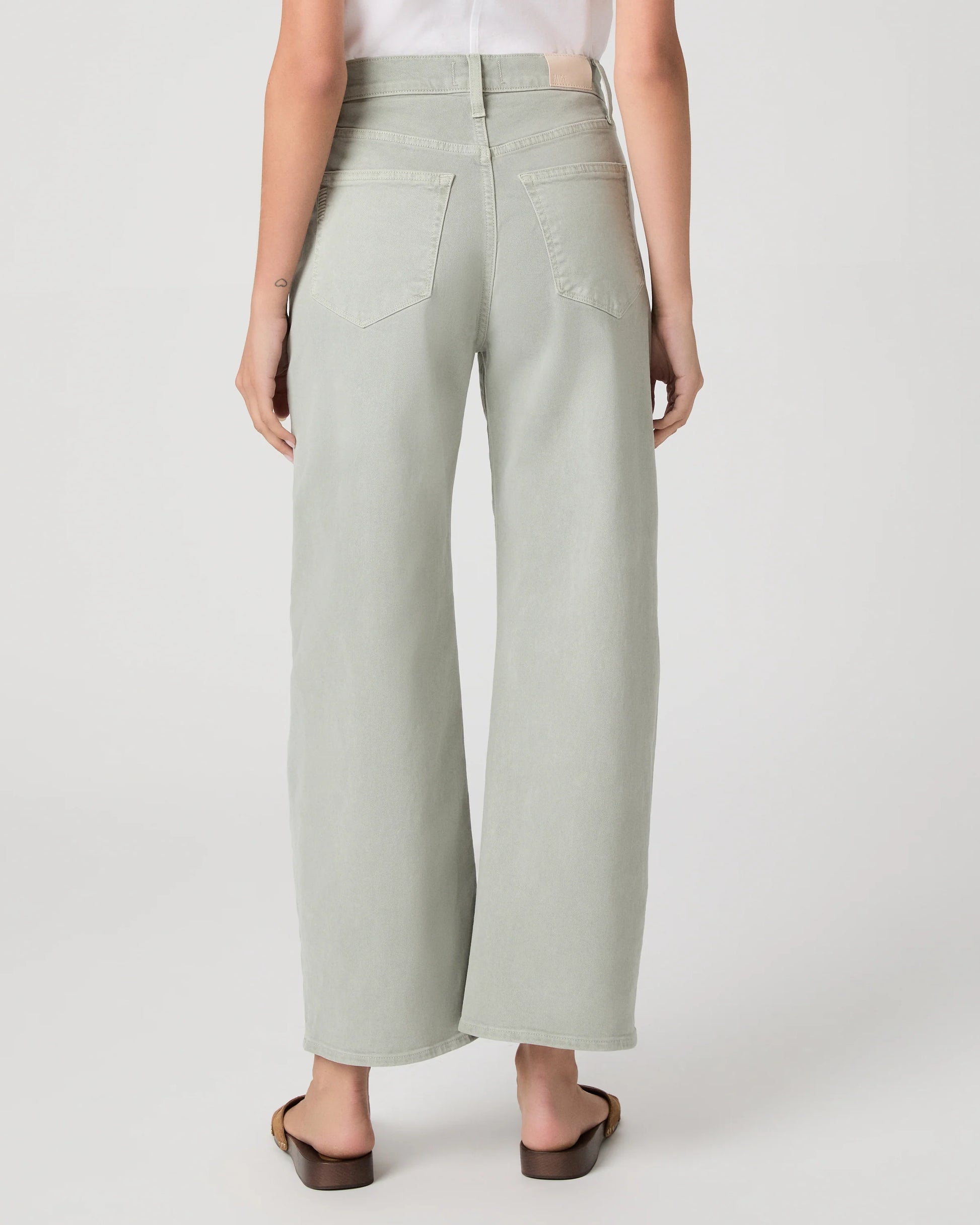 Person wearing light green wide-leg paige jeans on a white background rear view