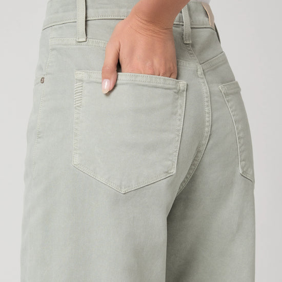 Person wearing light green wide-leg paige jeans on a white background close up