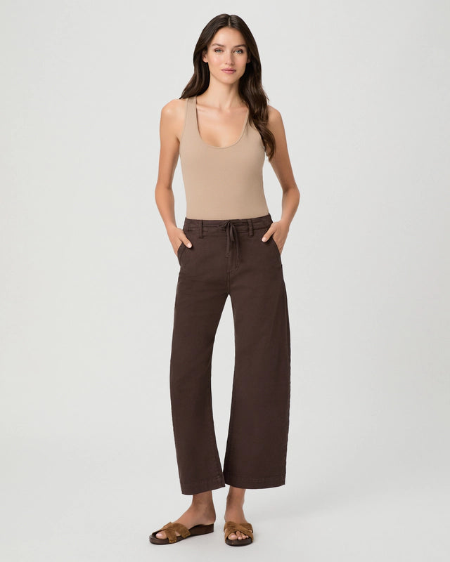 A woman modeling a beige ribbed tank top and dark brown wide-leg cropped pants with a drawstring waist, paired with brown slide sandals, against a light gray studio background.