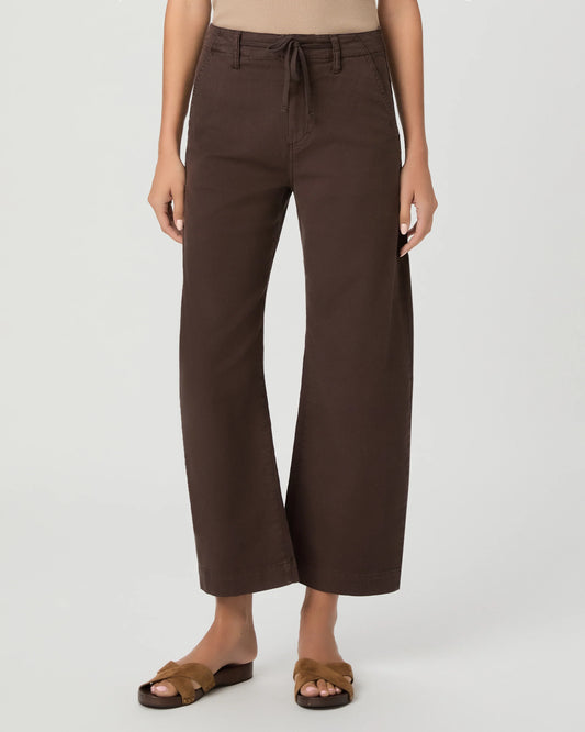 A model wearing dark brown wide-leg cropped pants with a drawstring waist, paired with brown slide sandals, against a light gray studio background.