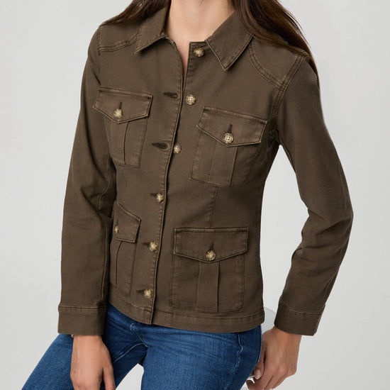 A woman wearing a dark brown utility-style jacket with four front flap pockets and brass-tone buttons, paired with blue jeans, photographed against a light gray studio background.