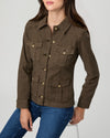 A woman wearing a dark brown utility-style jacket with four front flap pockets and brass-tone buttons, paired with blue jeans, photographed against a light gray studio background.