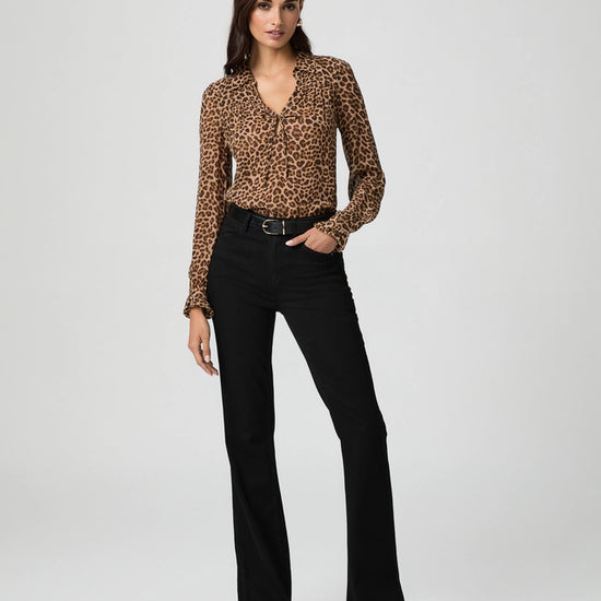 Woman wearing a leopard print top and black pants on a white background