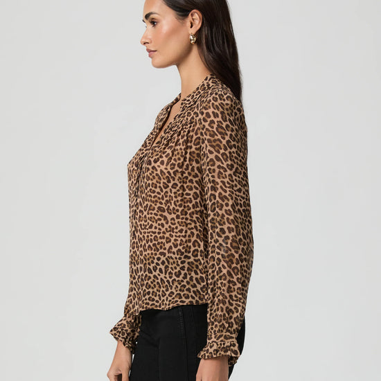 Side view woman wearing a leopard print blouse against a plain background