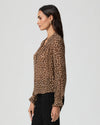 Side view woman wearing a leopard print blouse against a plain background
