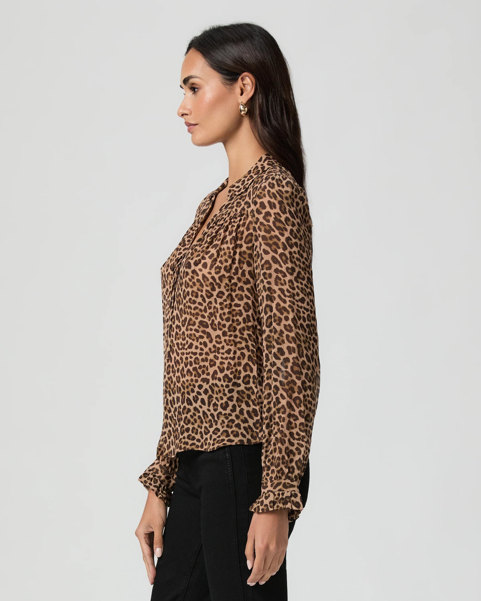 Side view woman wearing a leopard print blouse against a plain background