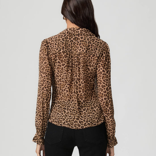 Rear view woman wearing a leopard print blouse against a plain background