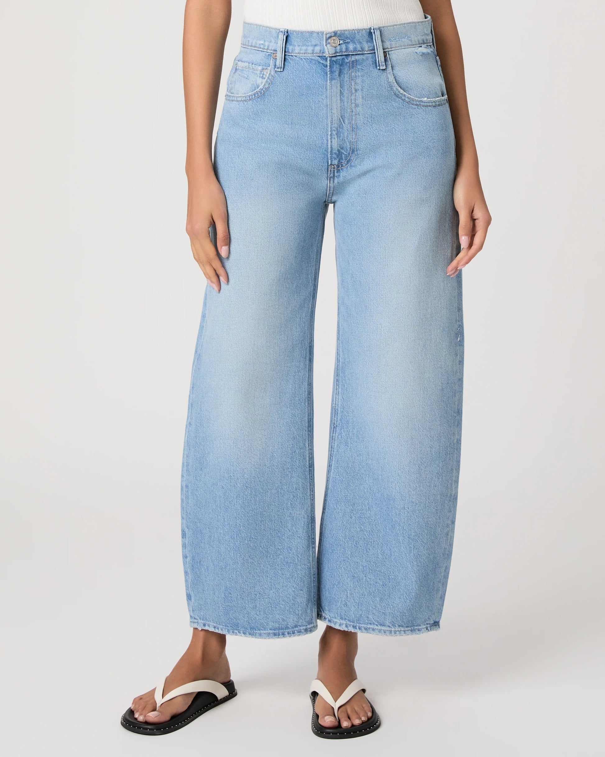 Light blue barrel leg jeans worn by a person on a white background from Paige