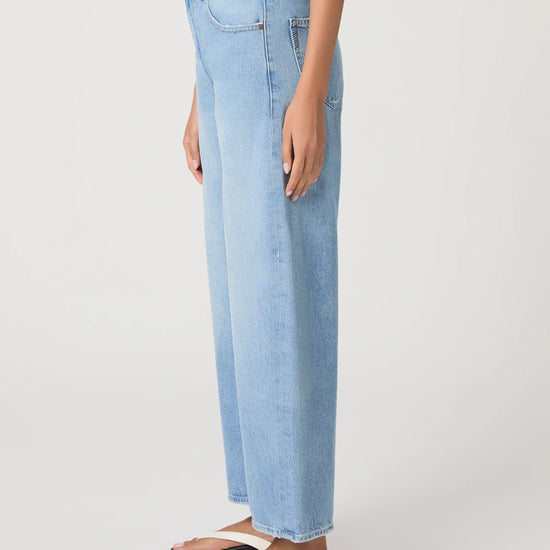 Light blue barrel leg jeans worn by a person on a white background