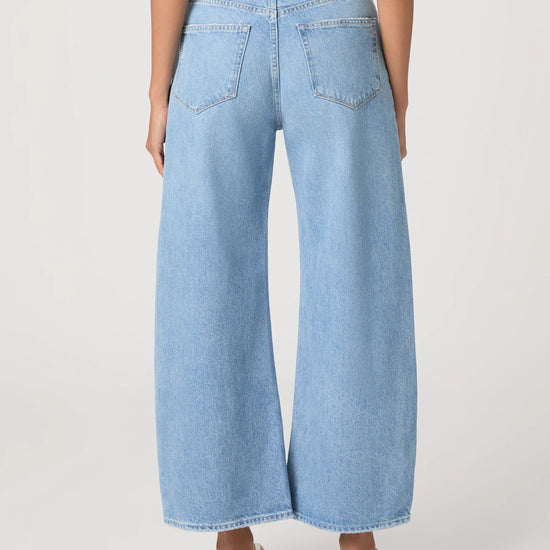 Light blue barrel-leg jeans worn by a person on a white background